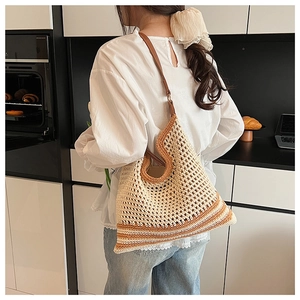 Detail of hand-woven straw tote with orange stripes and brown leather shoulder straps