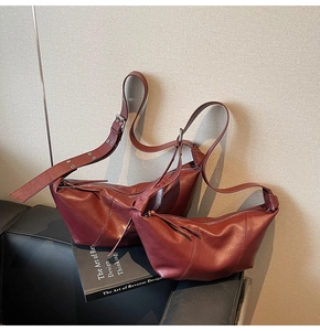 Detail of dark red crescent bags set in faux leather texture with tassel and silver buckle