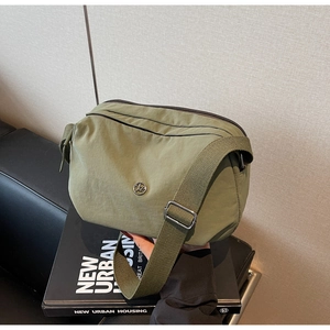 Sac bandoulière en nylon vert olive avec logo en métal sur des livres pour un look urbain