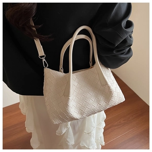 Gros plan du sac cabas beige en cuir tressé avec motif croisé et finitions argentées
