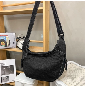 Detail of black denim hobo bag showing adjustable strap and white contrast stitching