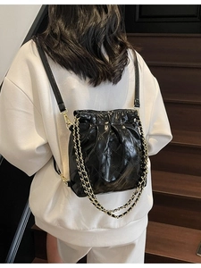 Sac à dos seau chic en cuir noir matelassé avec bretelles en chaîne dorée sur mannequin