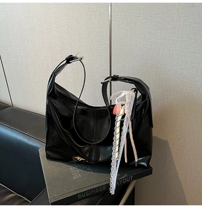 Detail of high-gloss black patent hobo bag with lace accents and adjustable silver buckle