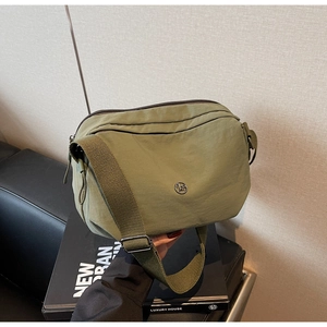 Détail du sac bandoulière en nylon vert foncé avec logo en métal et large sangle