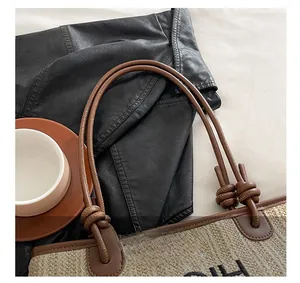 Detail of straw tote bag featuring brown leather handles with knot accents and CH embroidery