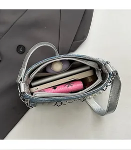 Detail of blue denim shoulder bag interior with spacious compartment and pearl decor
