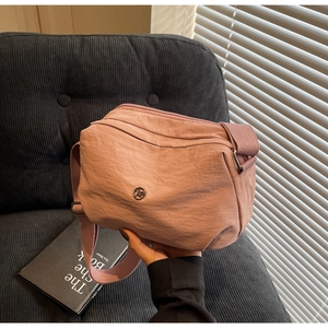 Détail du sac bandoulière en nylon rose poudré avec logo métallique et sangle réglable