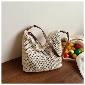 Close-up of hollow crochet texture and brown leather straps on the straw tote bag