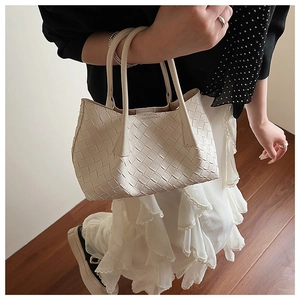 Détail d'un cabas en cuir tressé beige avec larges bandes et anses structurées