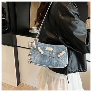 Sac à épaule en jean bleu clair avec chaîne de perles porté par un mannequin