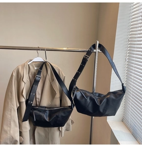 Detail view of black crescent moon bag with silver grommet adjustable strap on hanger