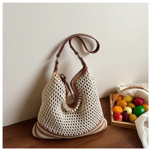 Detailed close-up of beige hollow knit straw tote bag with brown leather straps