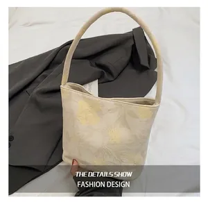 Detailed macro view of beige bucket bag with yellow floral patterns and single shoulder strap