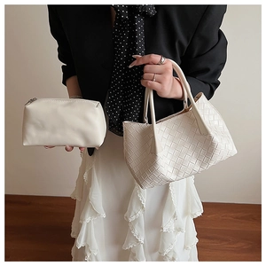 Détail d'un sac à main blanc tressé et d'une petite pochette à fermeture éclair assortie