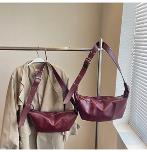 Detail of burgundy leather crescent bags in two sizes with adjustable wide straps