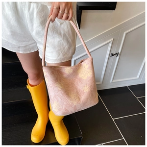Detail of light pink floral bucket bag with yellow prints and fabric texture