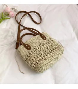 Detail of hand-woven straw bucket bag with brown leather handles and drawstring closure