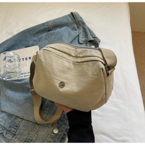 Détail du sac bandoulière en nylon beige avec sangle large et poches zippées