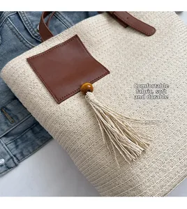 Detail of hand-woven straw tote bag with brown leather patch and soft wooden bead tassel