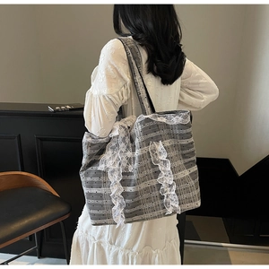 Détail du sac cabas gris à carreaux avec des finitions en dentelle blanche élégante