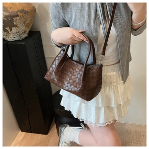 Vue détaillée du sac cabas tressé marron foncé avec poignée ronde et bandoulière en cuir