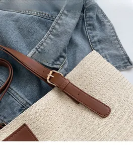 Detail of premium golden metal buckle and woven texture on straw tote bag with leather strap