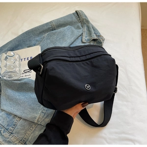 Détail du sac bandoulière en nylon noir avec double fermeture éclair et logo argenté