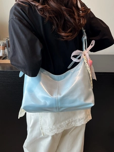 Light blue glossy hobo bag with lace bow and plaid scarf detail worn on shoulder