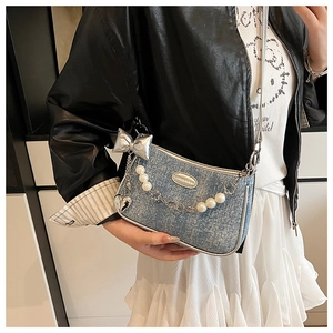 Détail du sac à bandoulière en denim avec chaînes de perles et breloques en métal