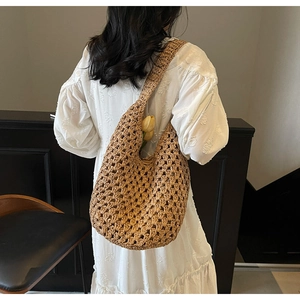 Detailed hollow woven texture of large brown straw shoulder bag with floral decoration