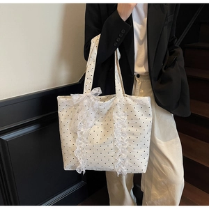 Détail d'un sac cabas en toile crème à pois noirs avec des finitions en dentelle blanche