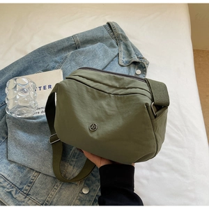 Détail du sac polochon en nylon vert sauge avec logo JP argenté et large bandoulière