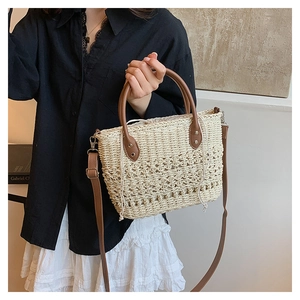 Detail of the woven straw bucket bag with brown leather handles and drawstring lining