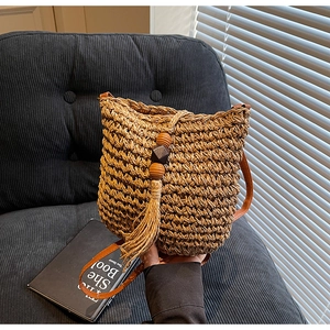 Dettaglio della borsa a secchiello in paglia con nappe boho e perline di legno decorative