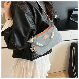 Détail du sac sous le bras en tweed bleu avec bordure en cuir rose et chaîne en perles