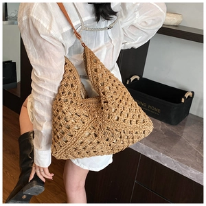 Detailed close-up of woven straw tote bag with geometric hollow patterns and leather strap