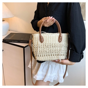 Close-up of hand-woven straw tote with brown leather handles and inner drawstring