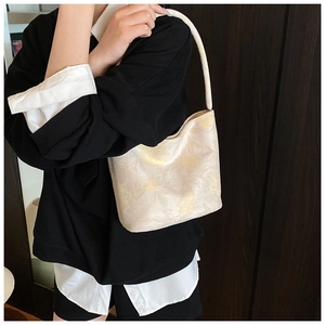 Detail of cream floral jacquard bucket bag showing the texture and premium embroidery