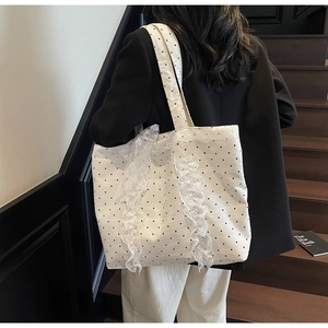 Sac cabas en toile à pois avec dentelle et nœud porté par un mannequin en escalier