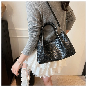 Détail du sac à main en cuir tressé noir montrant la texture et les boucles métalliques