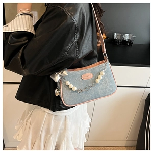 Détail du sac en jean bleu clair avec bandoulière perles et nœud argenté