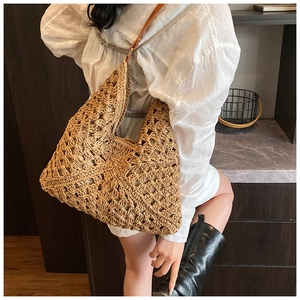 Close-up of handmade woven straw hobo bag featuring geometric hollow patterns and leather strap