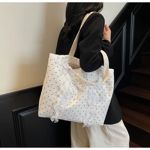 Grand sac cabas blanc à pois avec dentelle élégante porté par un mannequin