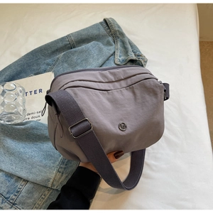 Détail d'un sac bandoulière en nylon lilas avec zips multicouches sur denim bleu