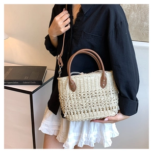 Close-up of beige woven straw tote bag with brown leather handles and inner drawstring bag