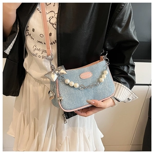 Détail du sac à bandoulière en denim bleu clair avec bordure rose et chaîne en perles