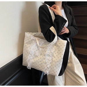Gros plan d'un sac cabas blanc à pois noirs avec des détails de dentelle blanche délicate