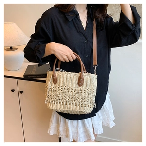 Detail of hand-woven straw bucket bag with dark brown leather handles and inner drawstring