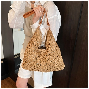 Close-up of hollow woven straw tote bag with thin leather shoulder straps and knit texture