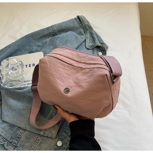 Gros plan sur le sac bandoulière en nylon rose avec fermetures éclair et bandoulière
